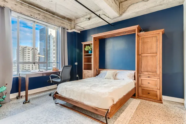 a bedroom with a bed and large windows