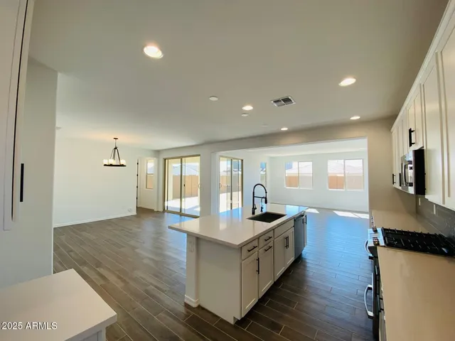 a large white kitchen with stainless steel appliances granite countertop a stove a sink and white cabinets