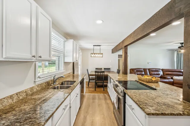 a kitchen with granite countertop white cabinets and a window