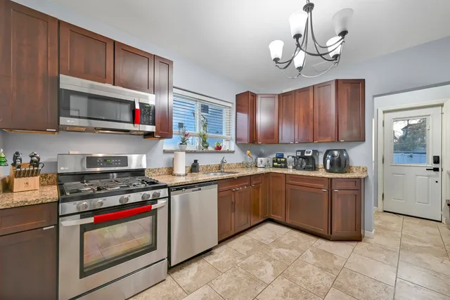 a kitchen with stainless steel appliances granite countertop a sink dishwasher stove and refrigerator with wooden floor