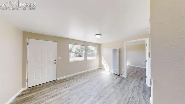 an empty room with wooden floor and windows