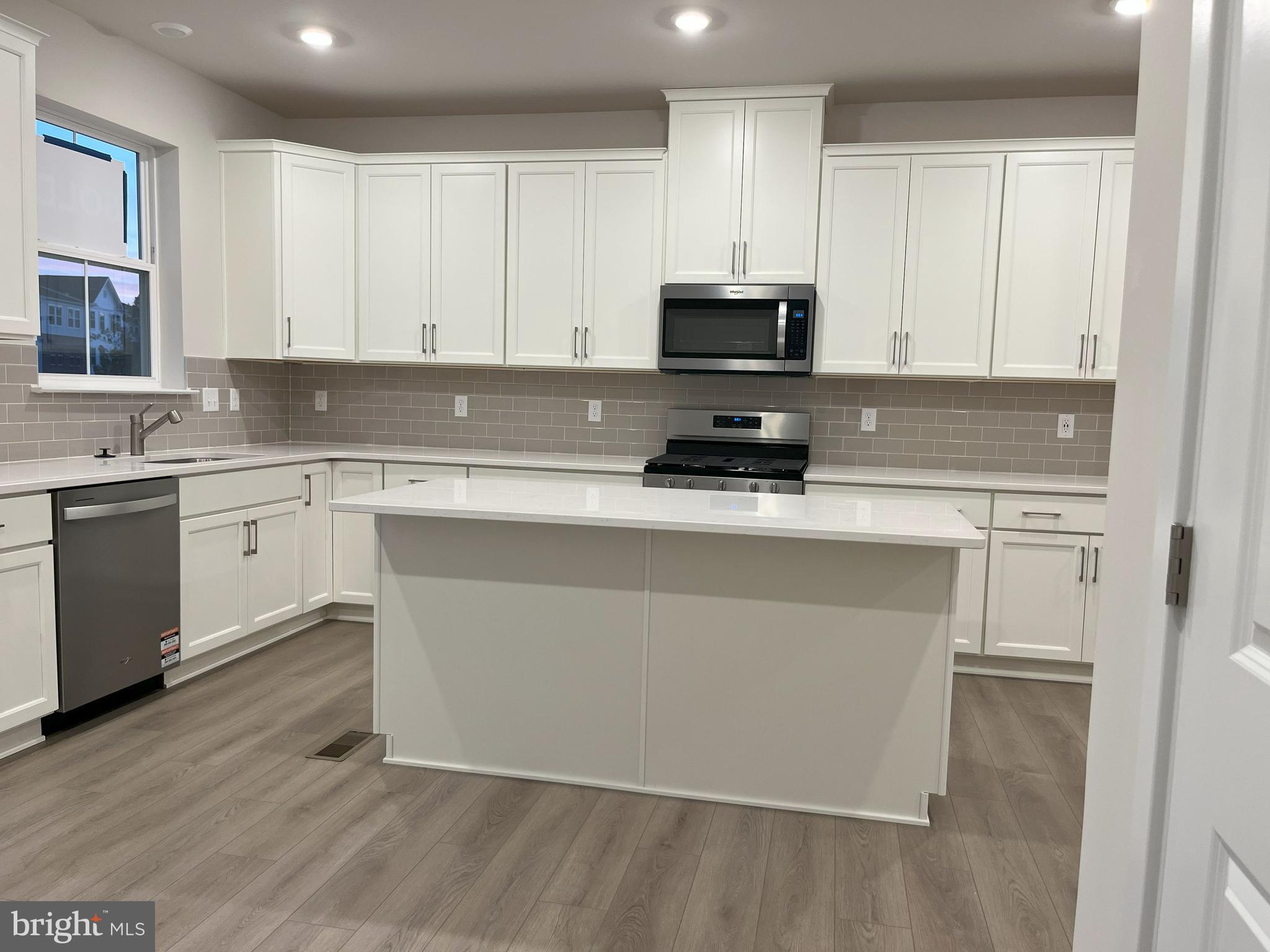 a kitchen with stainless steel appliances a stove top oven and white cabinets