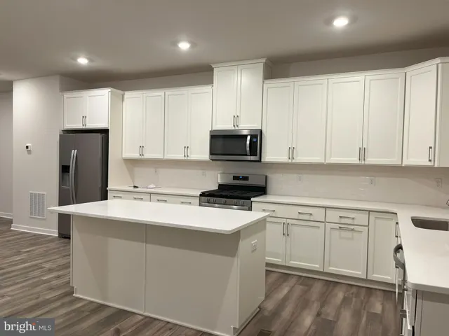 a kitchen with a sink a stove a refrigerator and white cabinets
