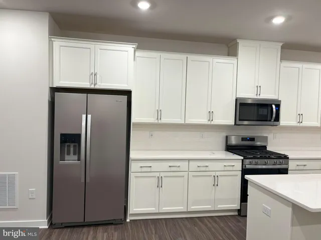 a kitchen with cabinets stainless steel appliances and wooden floor