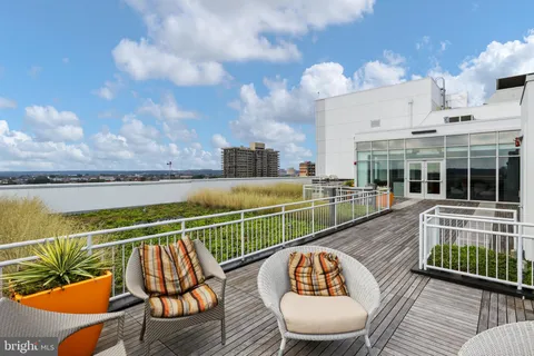 a view of a roof deck with table and chairs a barbeque with wooden floor and city view
