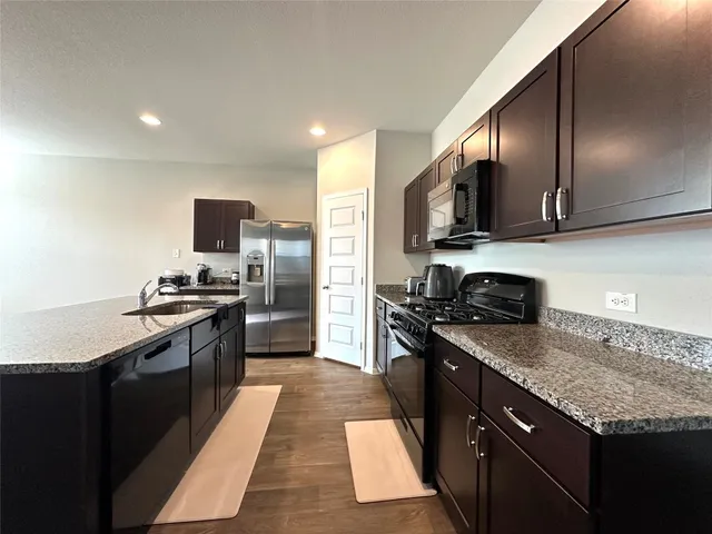 a kitchen with stainless steel appliances granite countertop a sink dishwasher a refrigerator microwave and stove