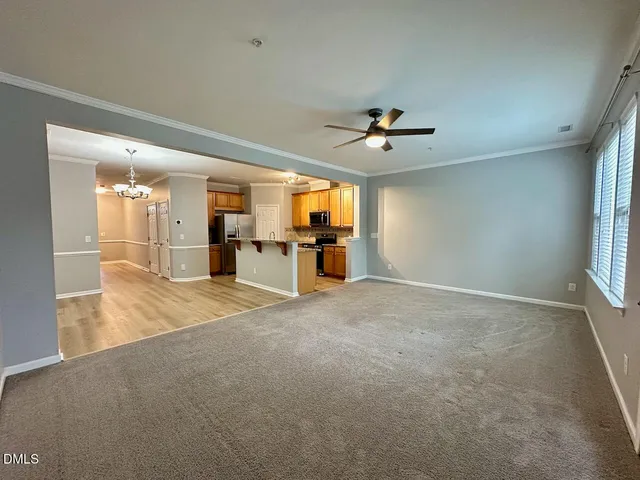 an empty room with chandelier fan and windows