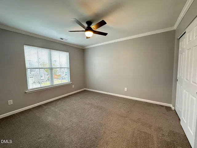 an empty room with windows and fan