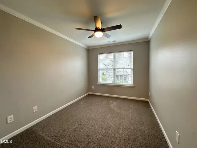 an empty room with ceiling fan and windows