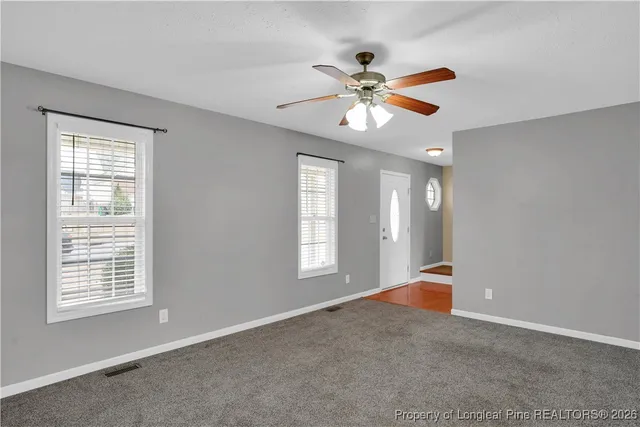 a view of an empty room with window and chandelier fan