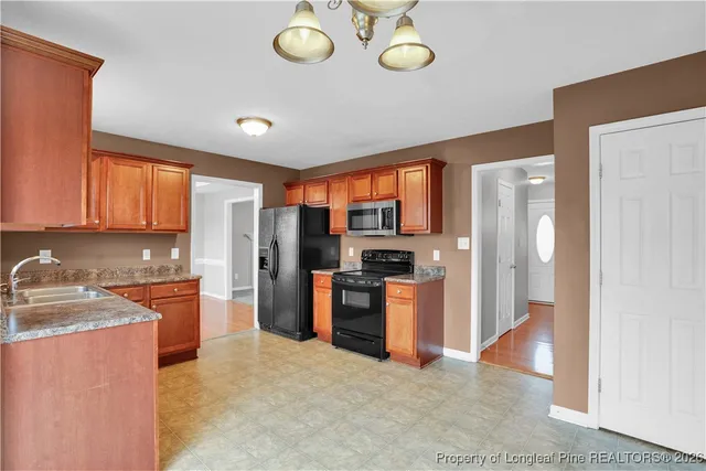 a kitchen with stainless steel appliances granite countertop a stove top oven a refrigerator and a sink