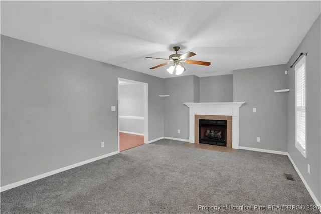 an empty room with a fireplace and chandelier fan