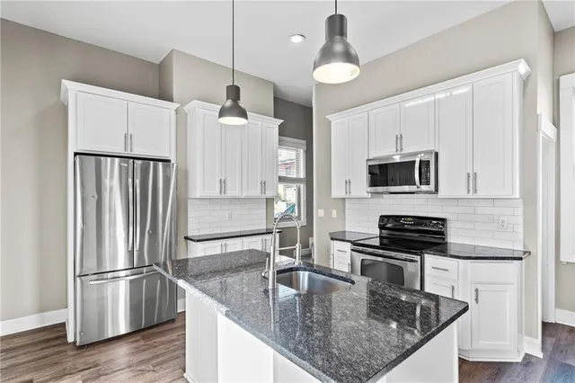 a kitchen with stainless steel appliances granite countertop a refrigerator a stove and a sink with wooden floor