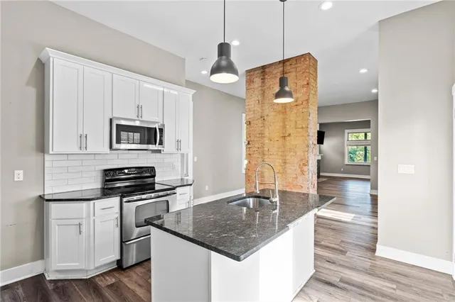 a kitchen with stainless steel appliances granite countertop a sink a stove and a wooden floors