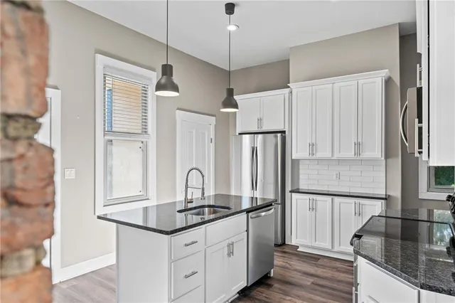 a kitchen with granite countertop a sink cabinets and stainless steel appliances