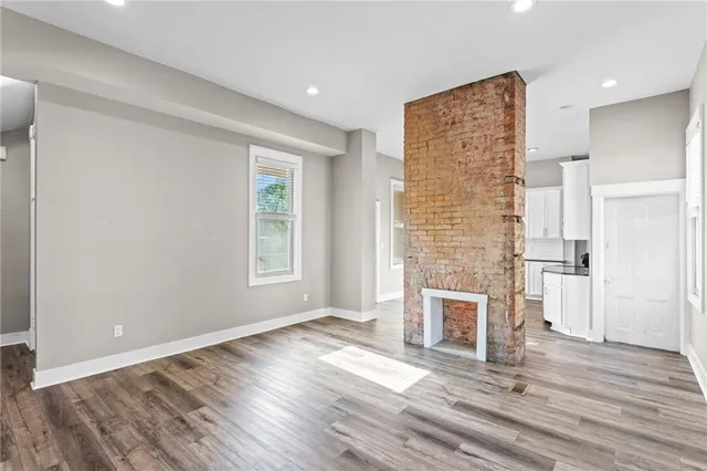 an empty room with wooden floor a fireplace and windows