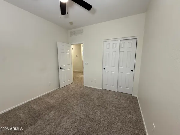 an empty room with ceiling fan and window