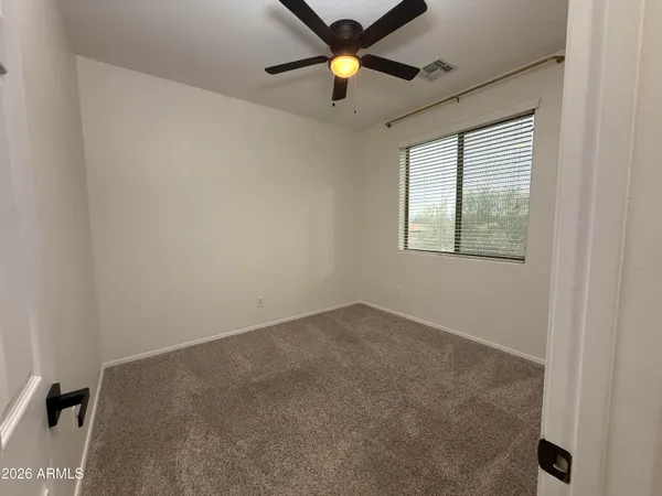 an empty room with window and a ceiling fan