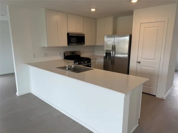 a view of a kitchen with a sink stove cabinets and empty room