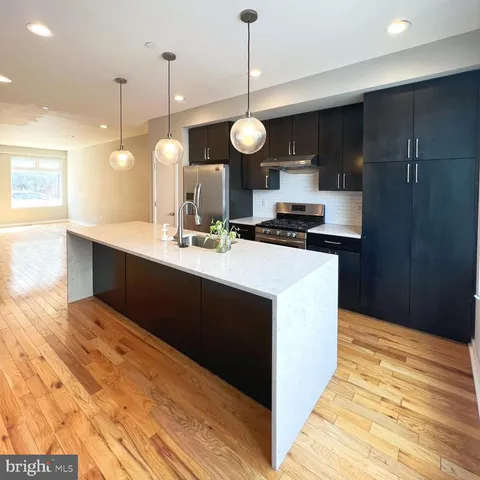 a kitchen with a sink a stove cabinets and wooden floor