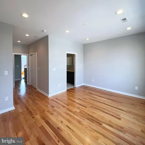 a view of an empty room with wooden floor and closet