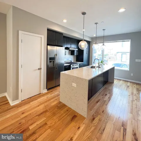a large kitchen with kitchen island a large counter top a sink stainless steel appliances and cabinets