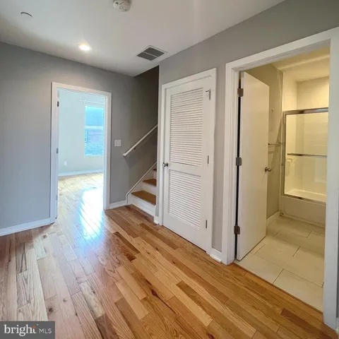 a view of a hallway with wooden floor and cabinet