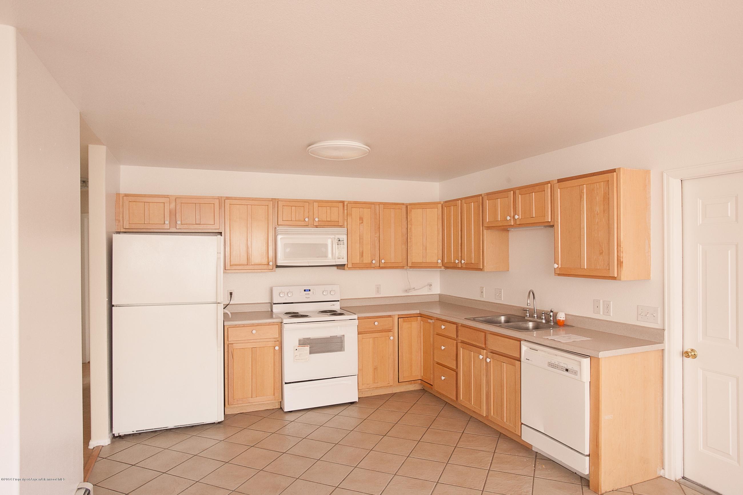 413 Evergreen Drive Rifle, CO 81650 - Photo 3 of 19 a kitchen with white cabinets a sink and white appliances