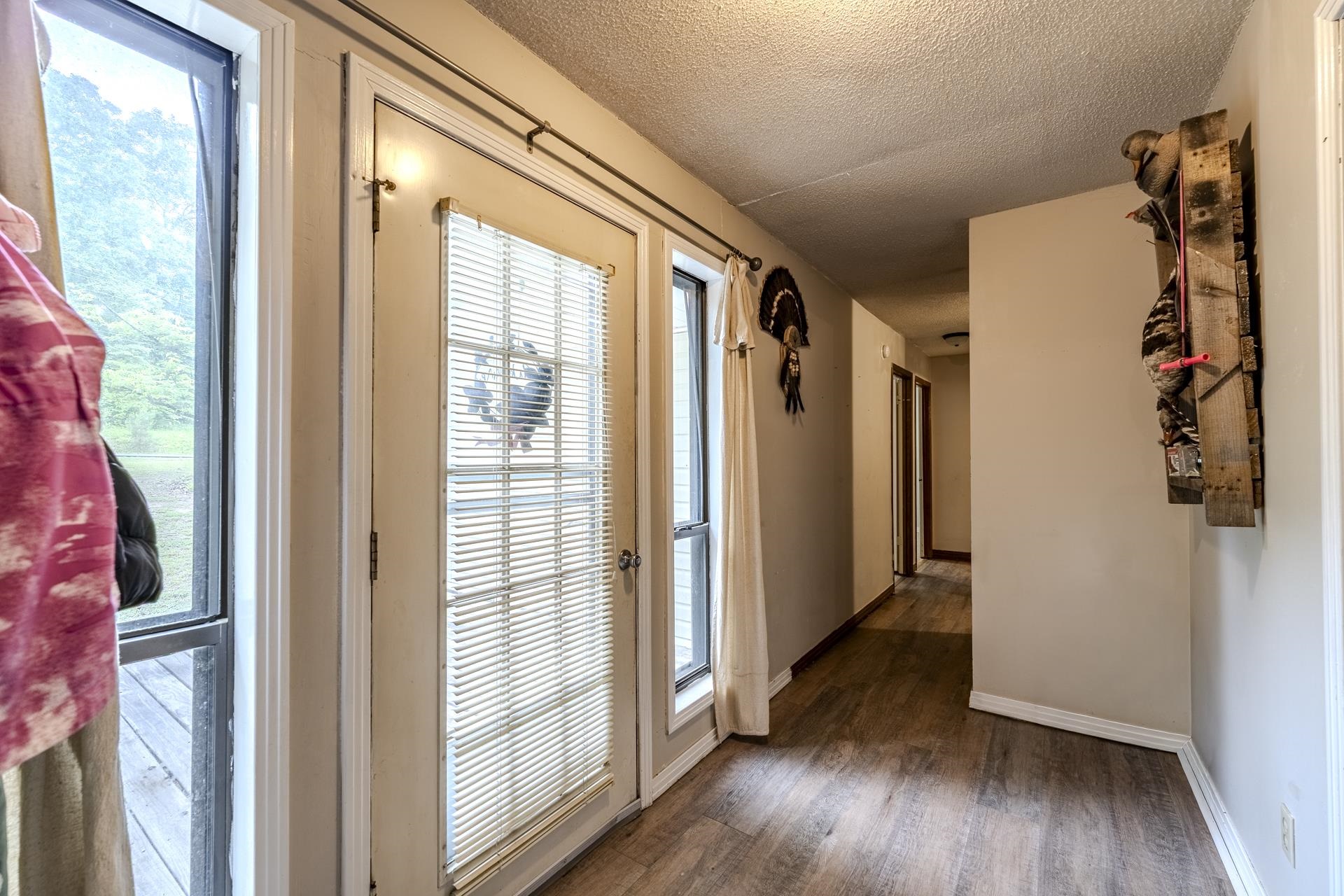 259 Oakview Drive Adamsville, TN 38310 - Photo 8 of 32 Entryway featuring a glass-paned door with blinds, an adjacent vertical window, and wood-finish flooring