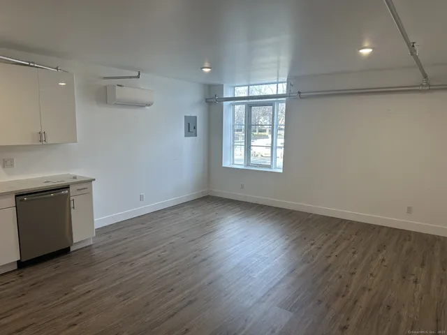 a view of an empty room with a window and wooden floor