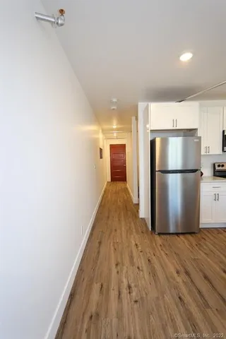 a view of a kitchen with a refrigerator and a wooden floor