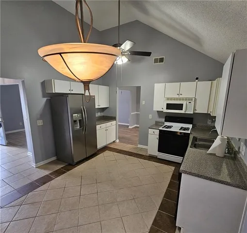 a kitchen with granite countertop a refrigerator a stove and a sink