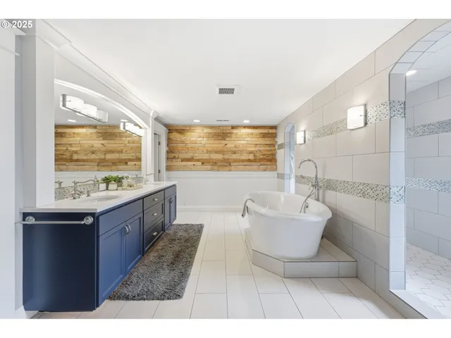 a bathroom with a tub sink shower and mirror