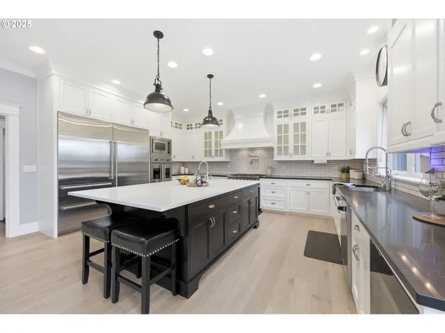 a kitchen with stainless steel appliances kitchen island granite countertop a sink a stove and a wooden floors