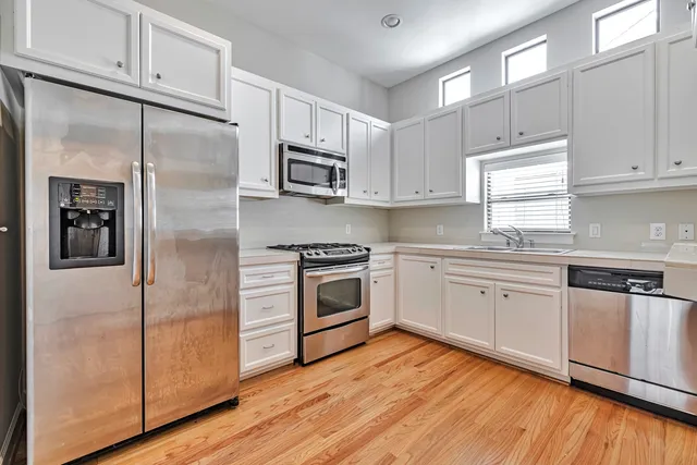 a kitchen with cabinets stainless steel appliances and wooden floor