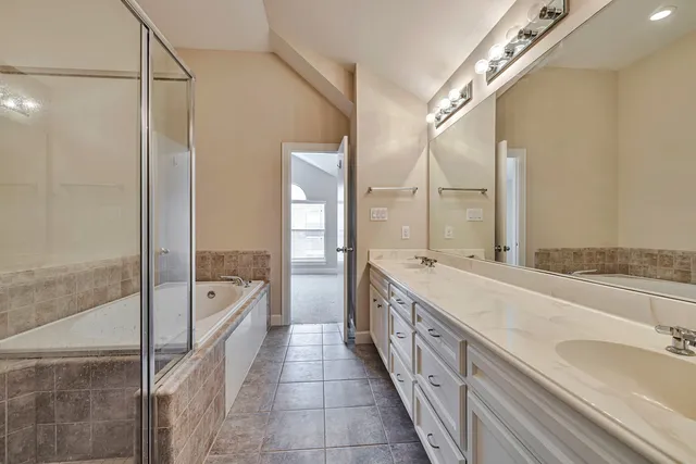 a bathroom with a double vanity sink a mirror and a bathtub