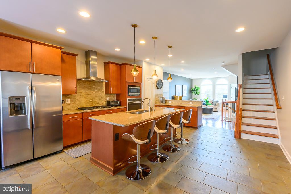 20649 Duxbury Terrace Ashburn, VA 20147 - Photo 18 of 41 a kitchen with stainless steel appliances kitchen island granite countertop a table chairs and a refrigerator