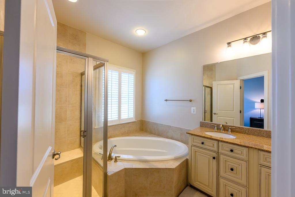 20649 Duxbury Terrace Ashburn, VA 20147 - Photo 29 of 41 a bathroom with a granite countertop sink mirror vanity bathtub and toilet