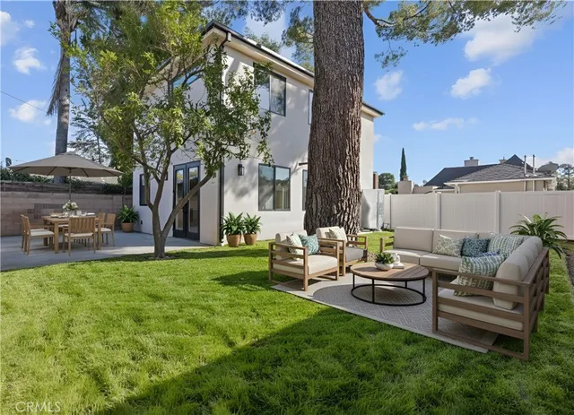 a view of a patio with couches and table and chairs with wooden fence and floor