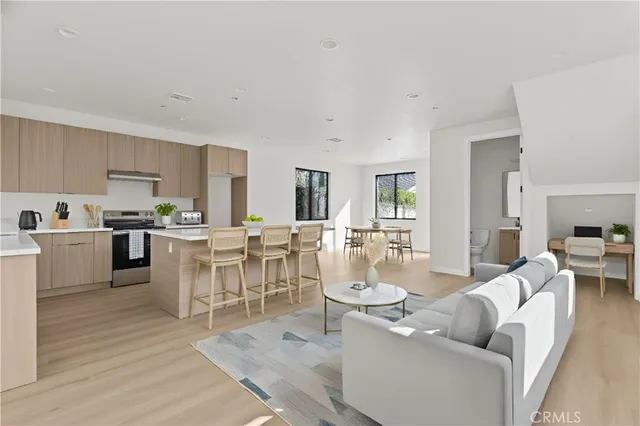 a living room with furniture a dining table wooden floor and a view of kitchen