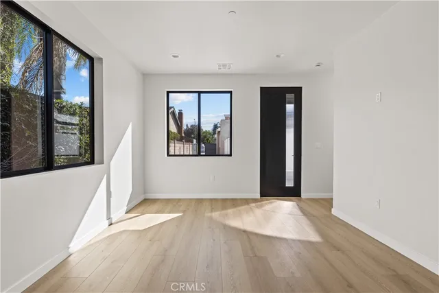 a view of empty room with wooden floor and fan