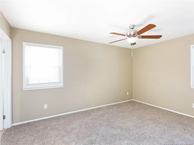 an empty room with a window and a ceiling fan