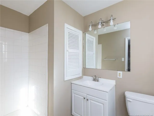 a bathroom with a toilet a sink a mirror a vanity and window