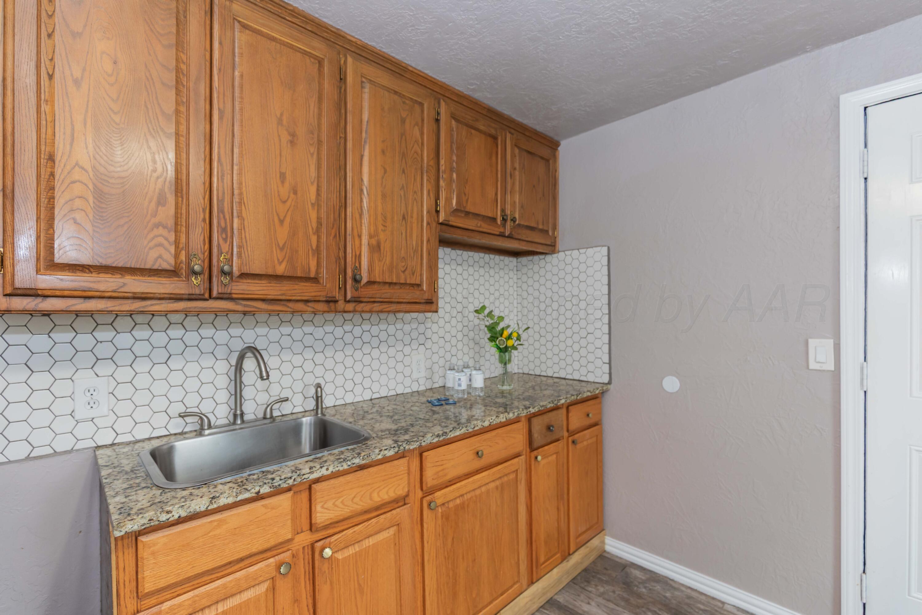 1307 North Buchanan Street Amarillo, TX 79107 - Photo 11 of 31 a kitchen with granite countertop stainless steel appliances a sink a refrigerator and cabinets