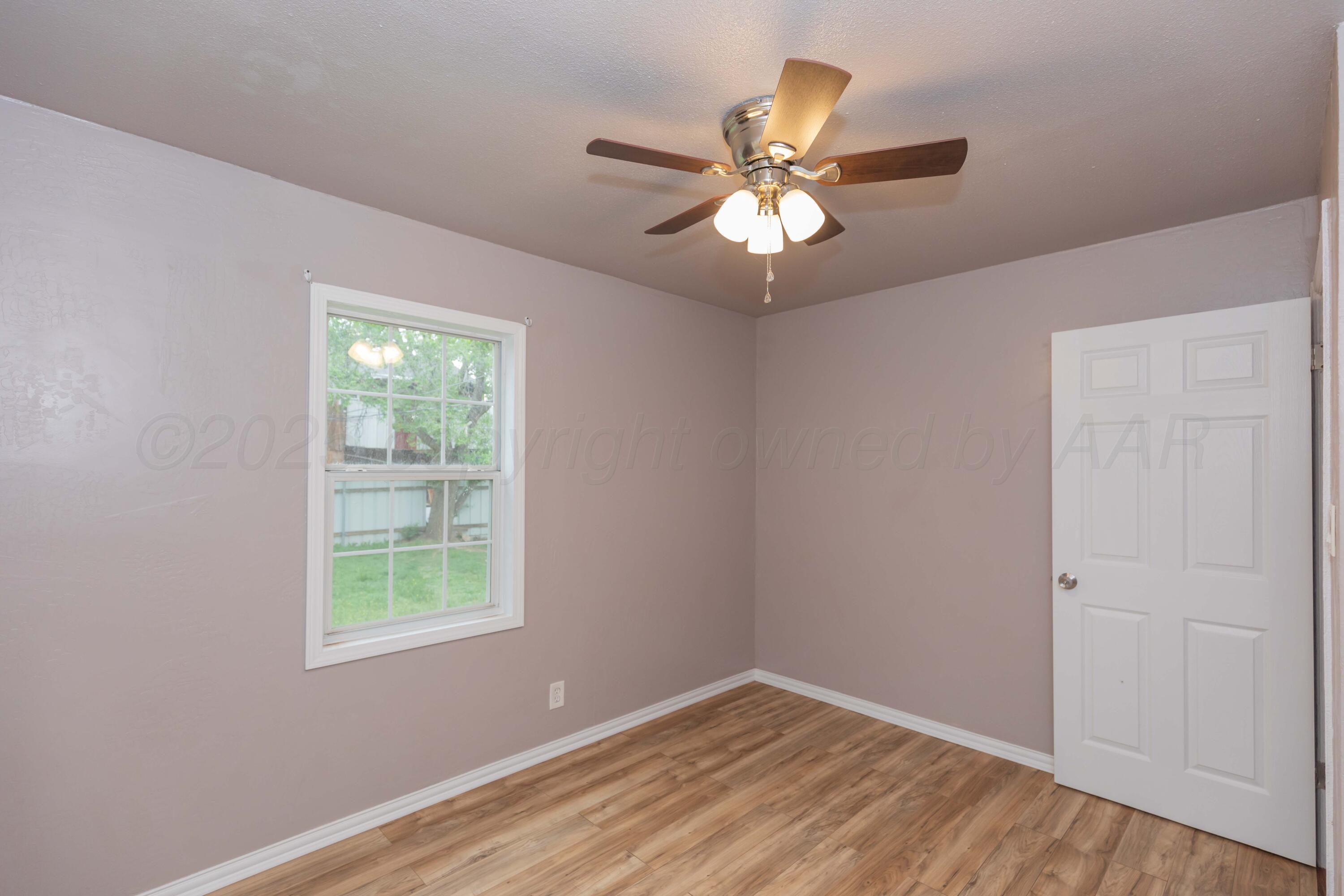 1307 North Buchanan Street Amarillo, TX 79107 - Photo 14 of 31 an empty room with wooden floor fan and windows