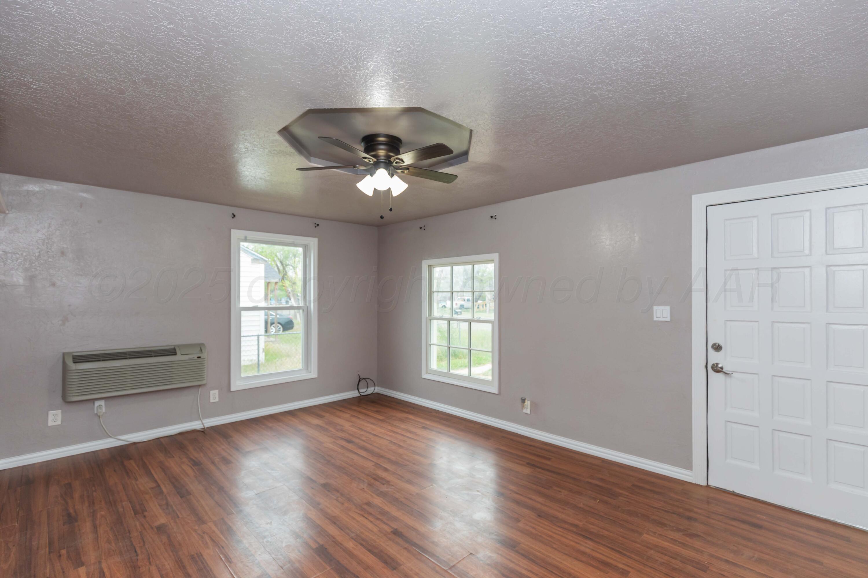 1307 North Buchanan Street Amarillo, TX 79107 - Photo 5 of 31 an empty room with wooden floor chandelier fan and windows