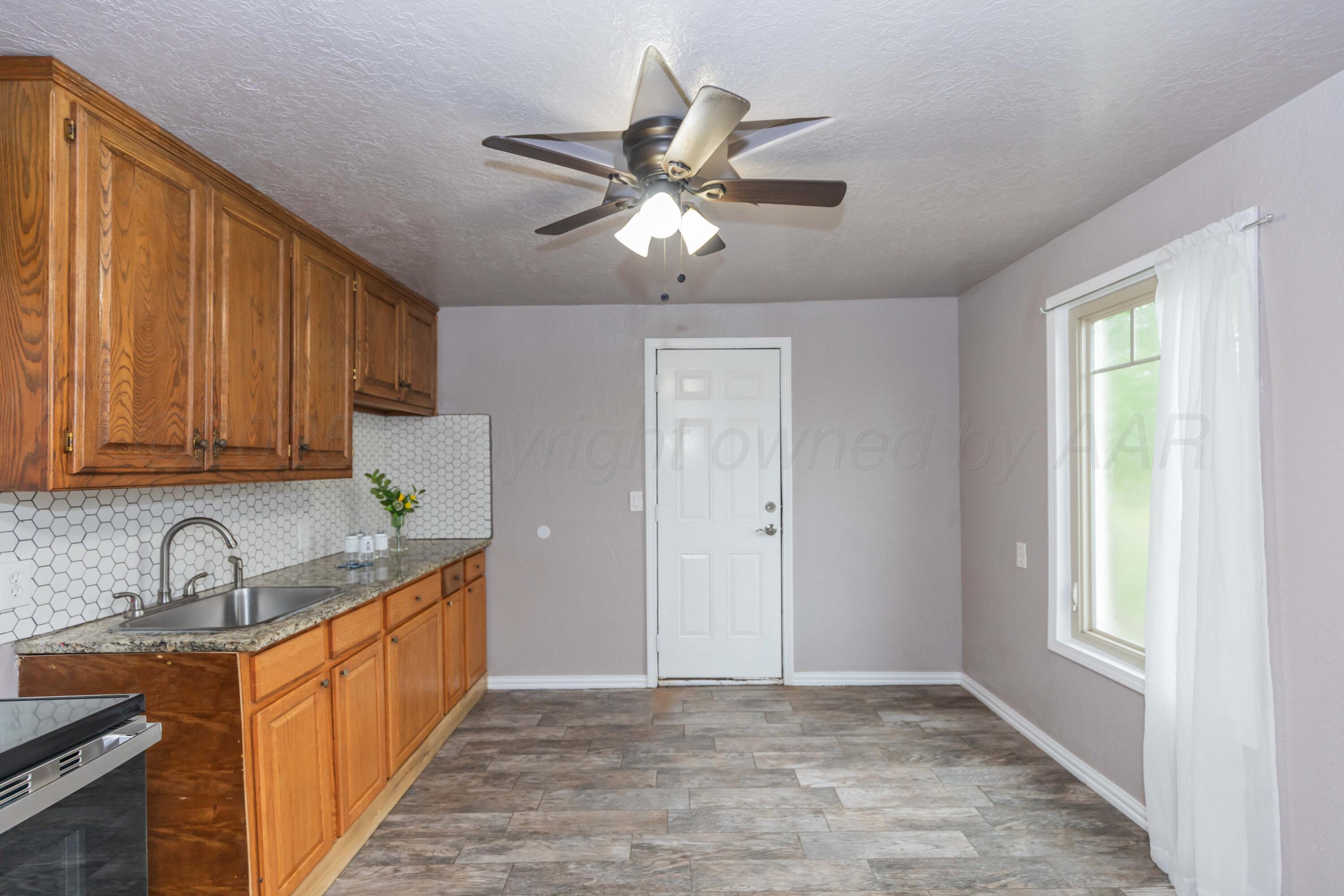 1307 North Buchanan Street Amarillo, TX 79107 - Photo 9 of 31 a kitchen with stainless steel appliances granite countertop a sink a stove cabinets and a window