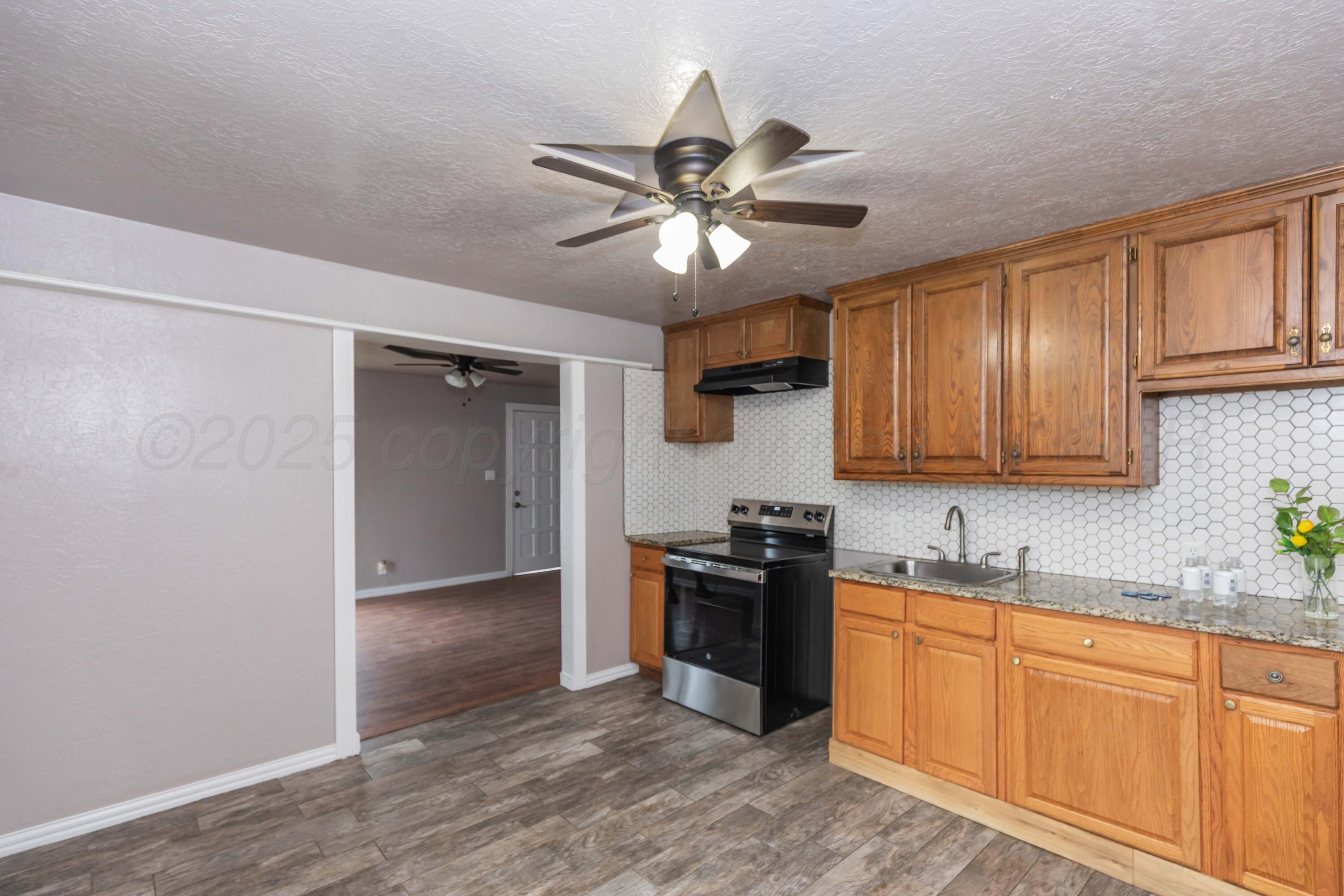 1307 North Buchanan Street Amarillo, TX 79107 - Photo 10 of 31 a kitchen with stainless steel appliances granite countertop a stove a sink and a refrigerator with wooden floors