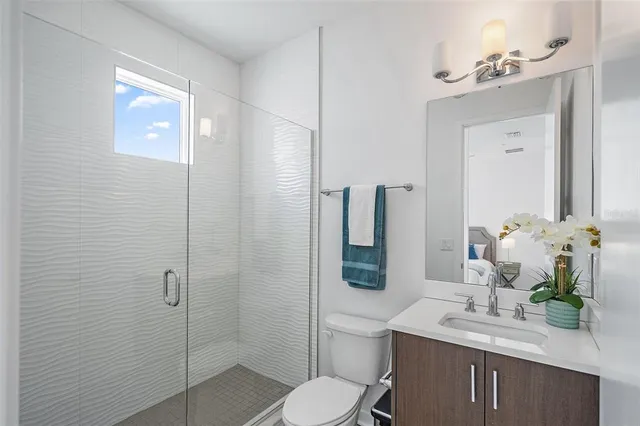 a bathroom with a sink vanity granite toilet and shower