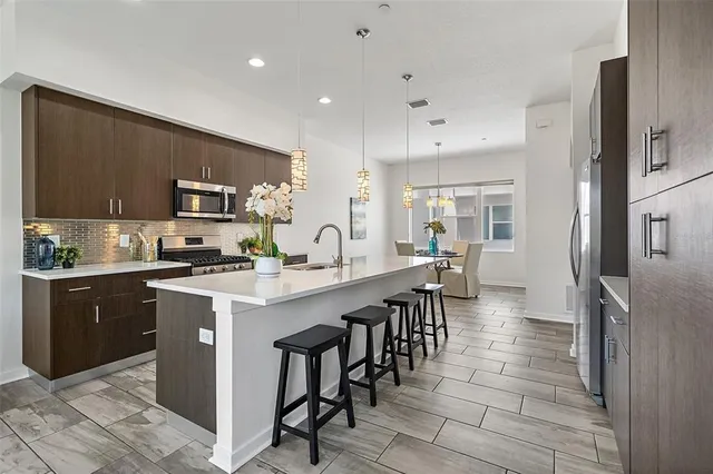 a large kitchen with cabinets chairs and a stainless steel appliances